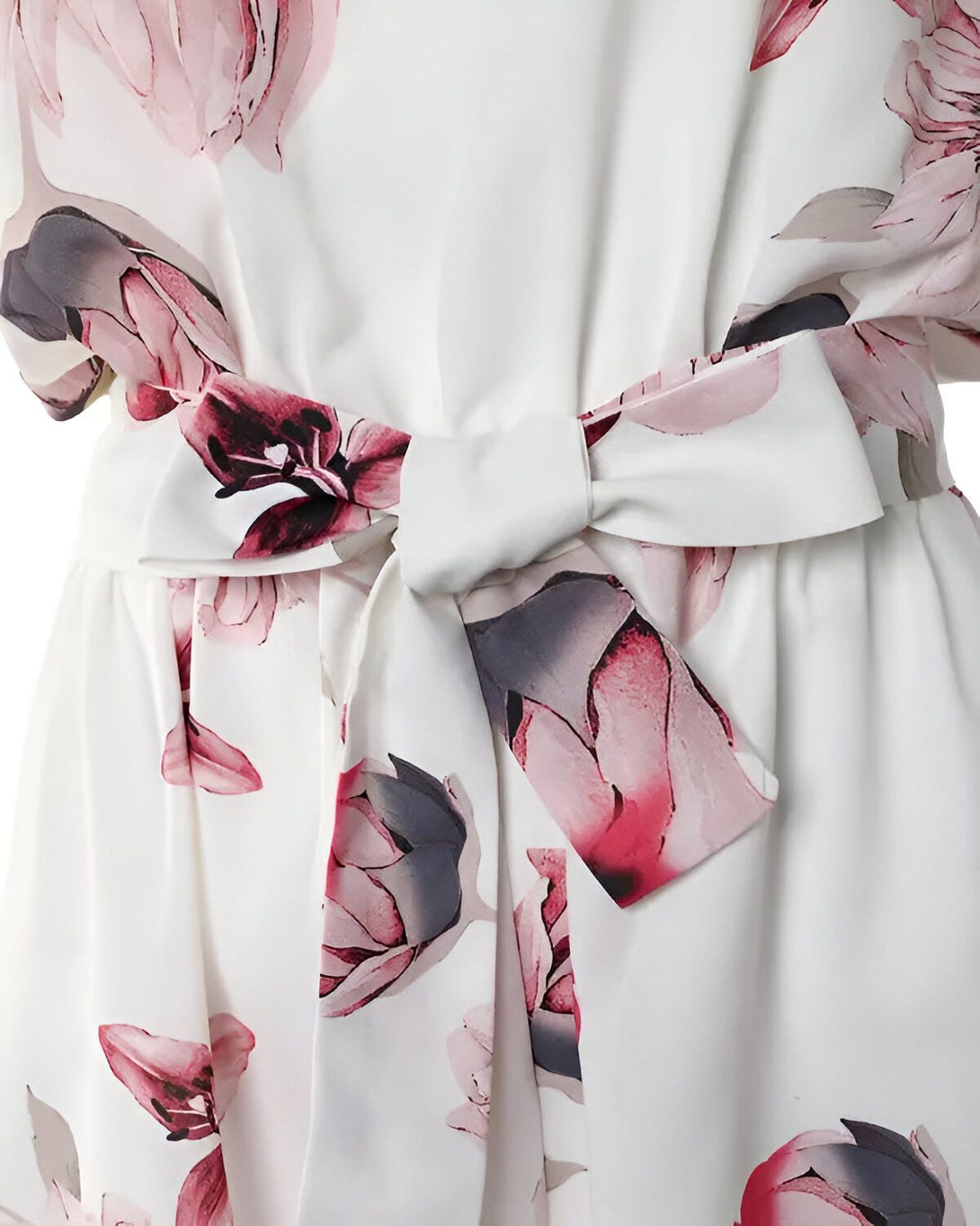 Une image d'une robe blanche à fleurs roses et grises. La robe est ceinturée d'un ruban blanc.