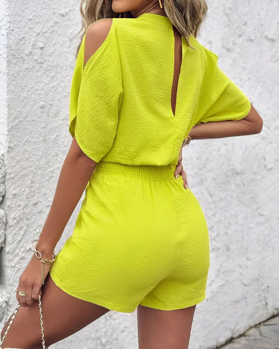 Une femme porte une combinaison short verte dos nu.