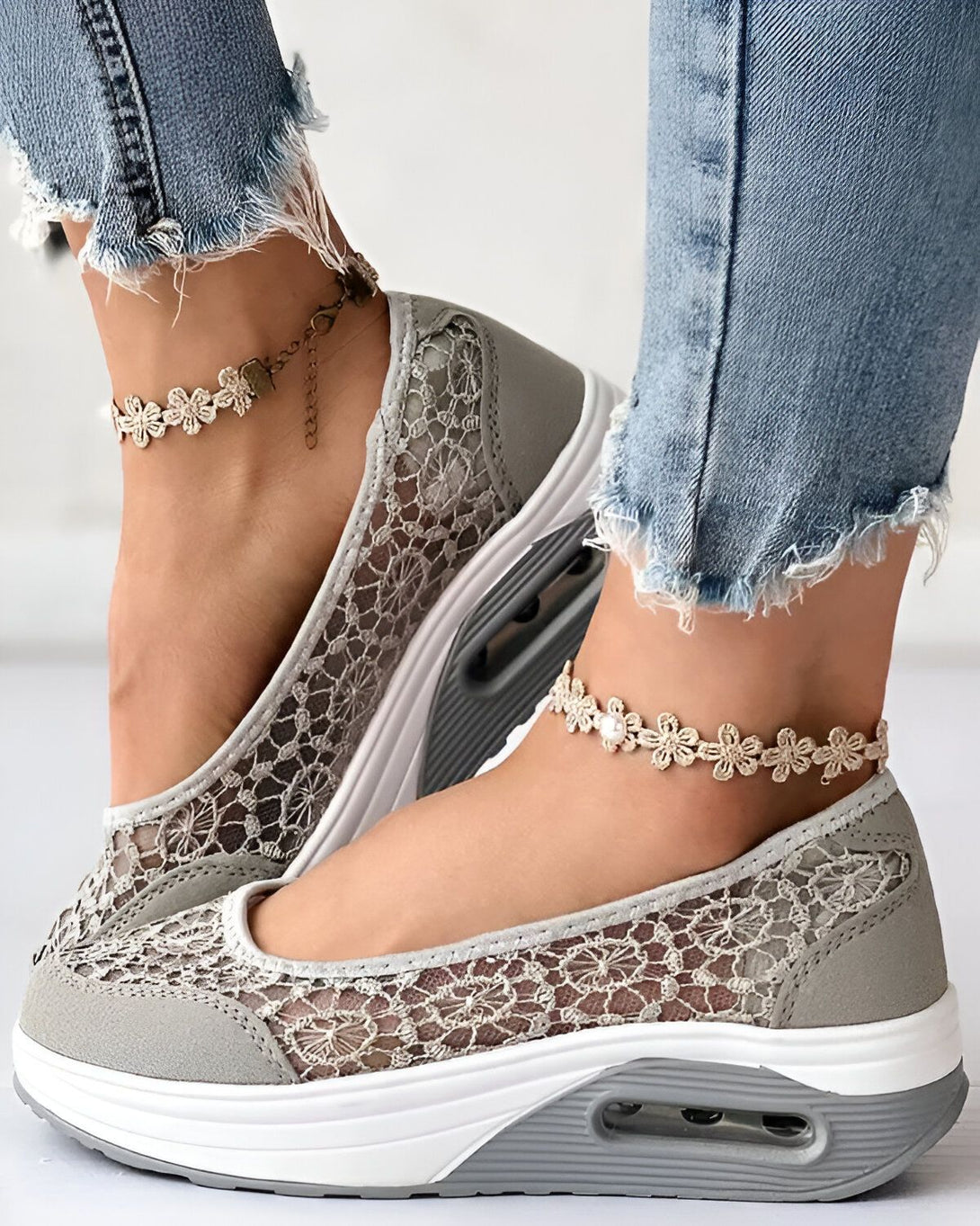 Une femme porte des chaussures de sport grises en dentelle avec des fleurs en dentelle sur les chevilles.