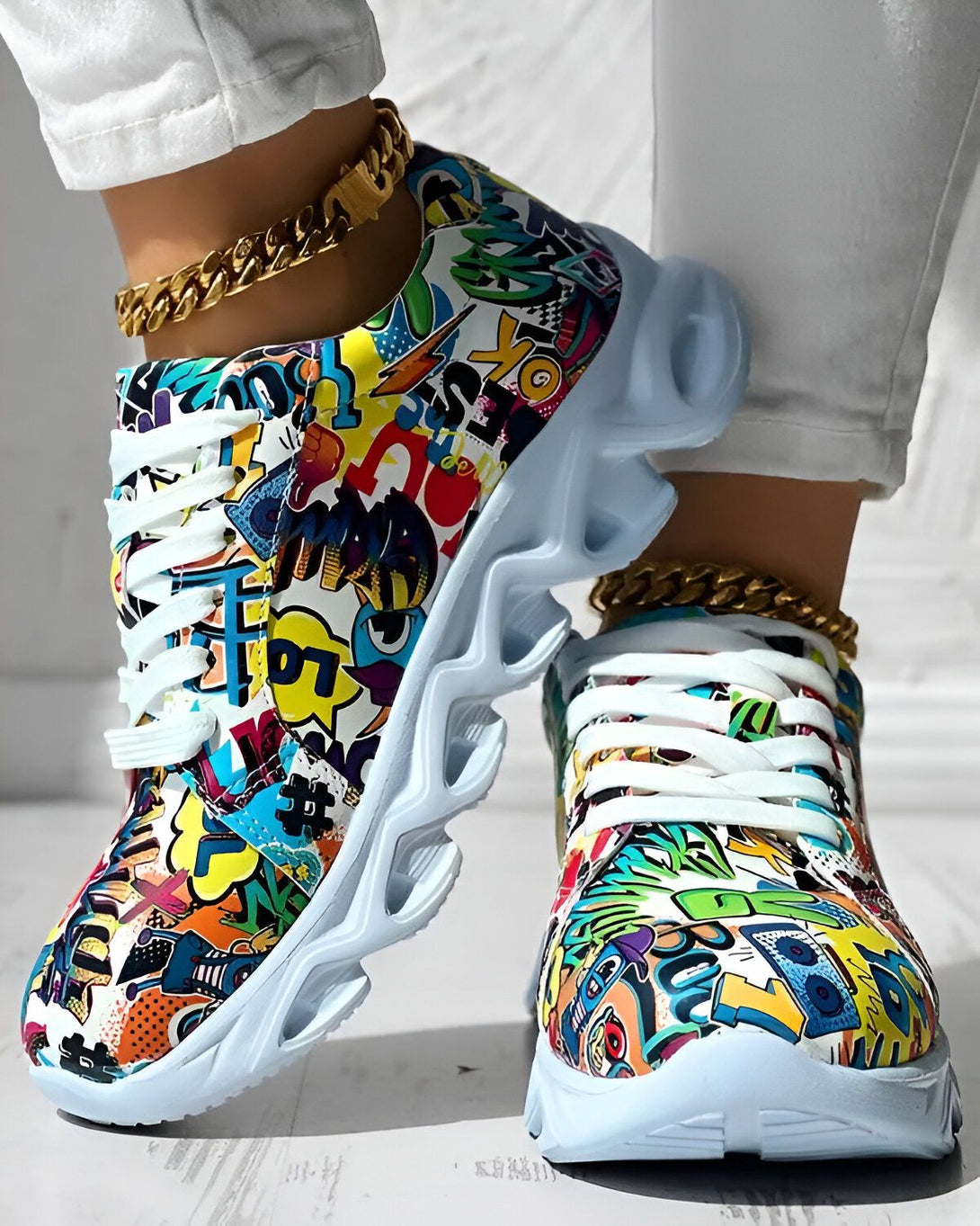 Une paire de baskets multicolores avec des lacets blancs et une semelle blanche. Les baskets sont portées par une femme qui porte un jean blanc et un haut blanc. La femme est debout sur un sol en béton.