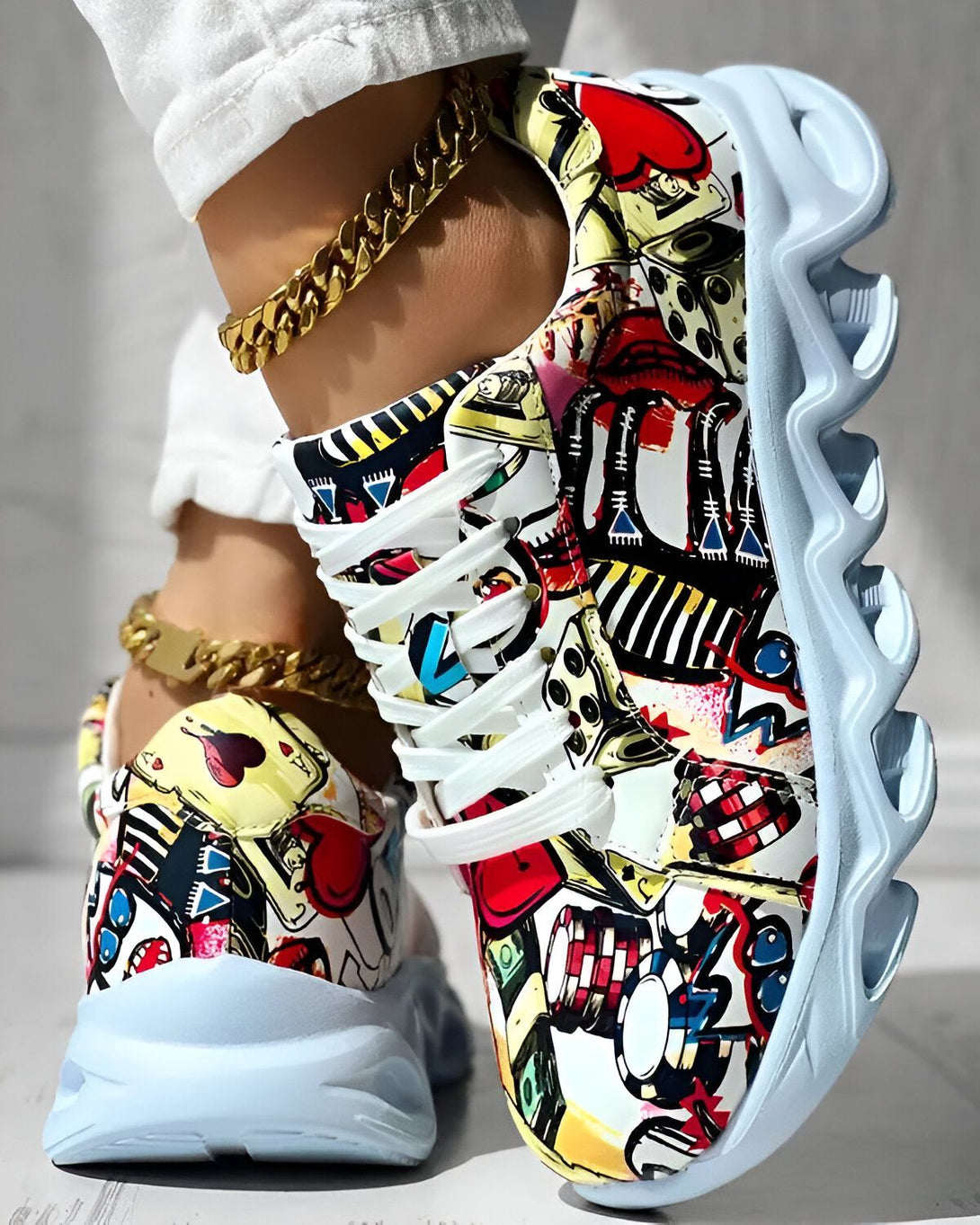 Une paire de baskets blanches et colorées avec des motifs de cartes à jouer, de dés et de lèvres rouges.