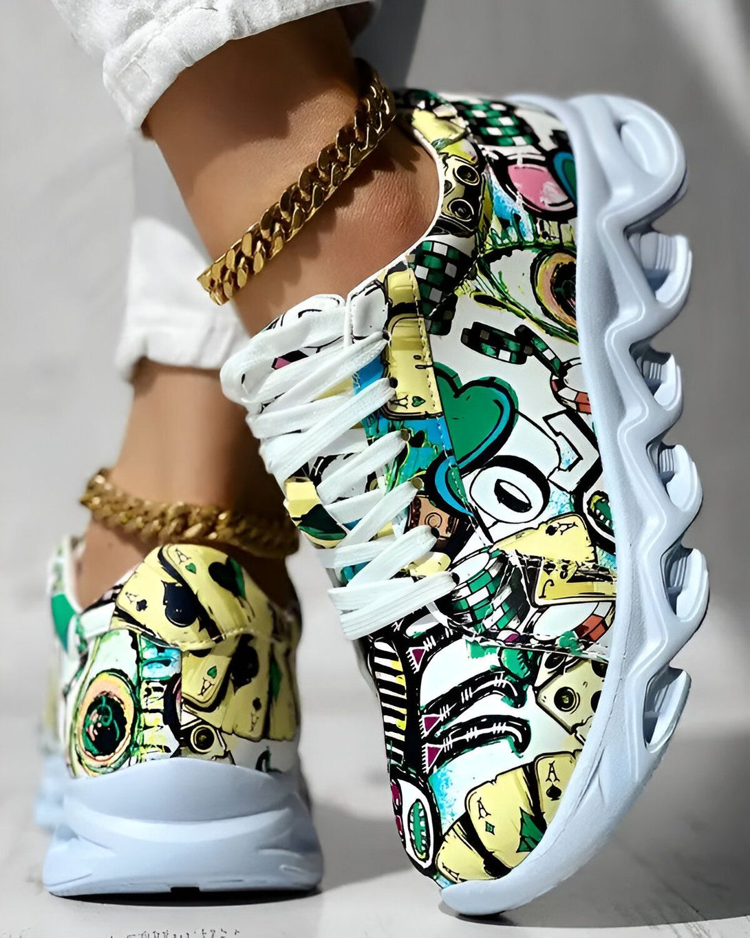 Une paire de baskets colorées avec des motifs de cartes à jouer et des chaînes en or.