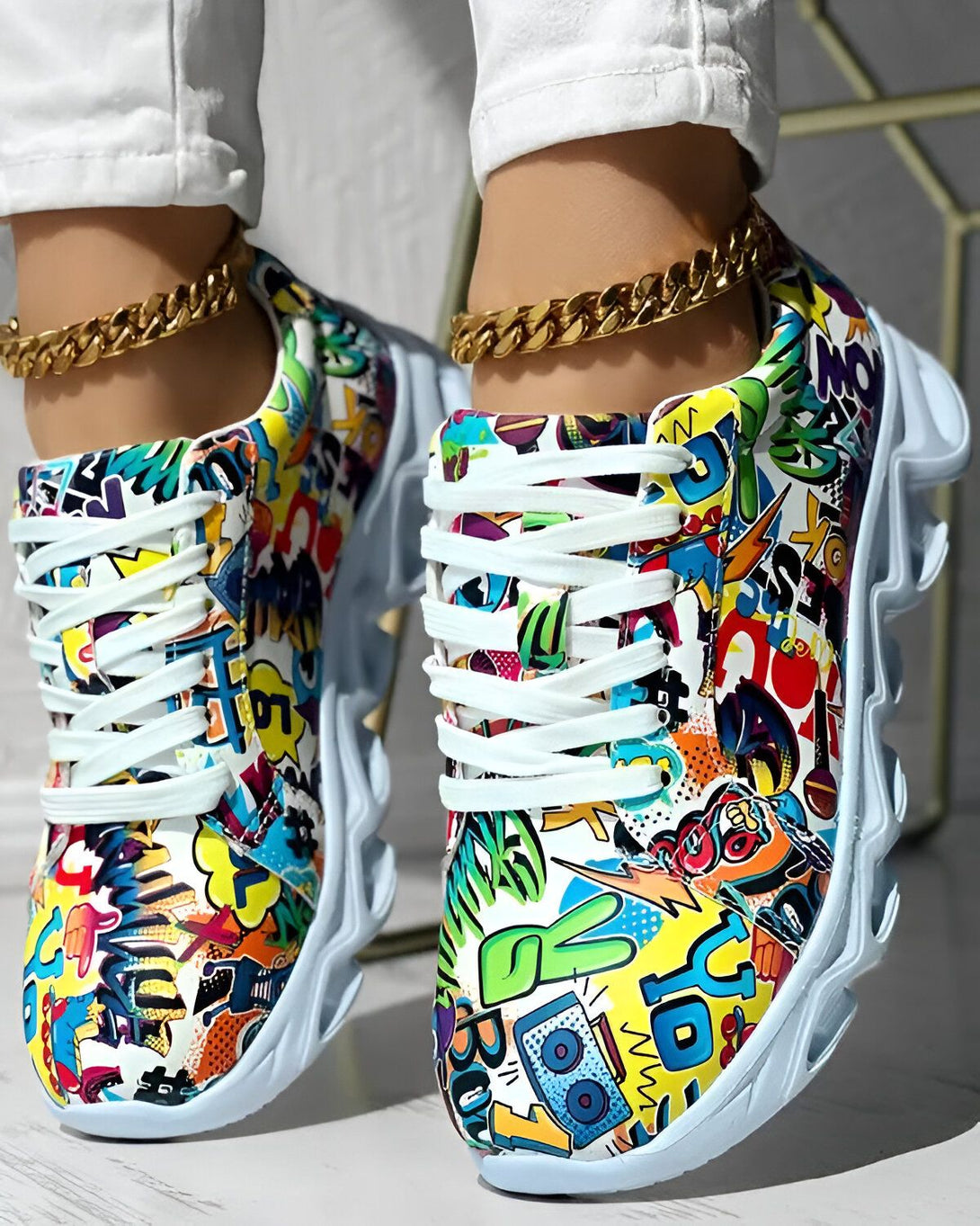 Une paire de baskets montantes colorées avec des lacets blancs et une semelle épaisse. Les baskets sont recouvertes de graffitis colorés.