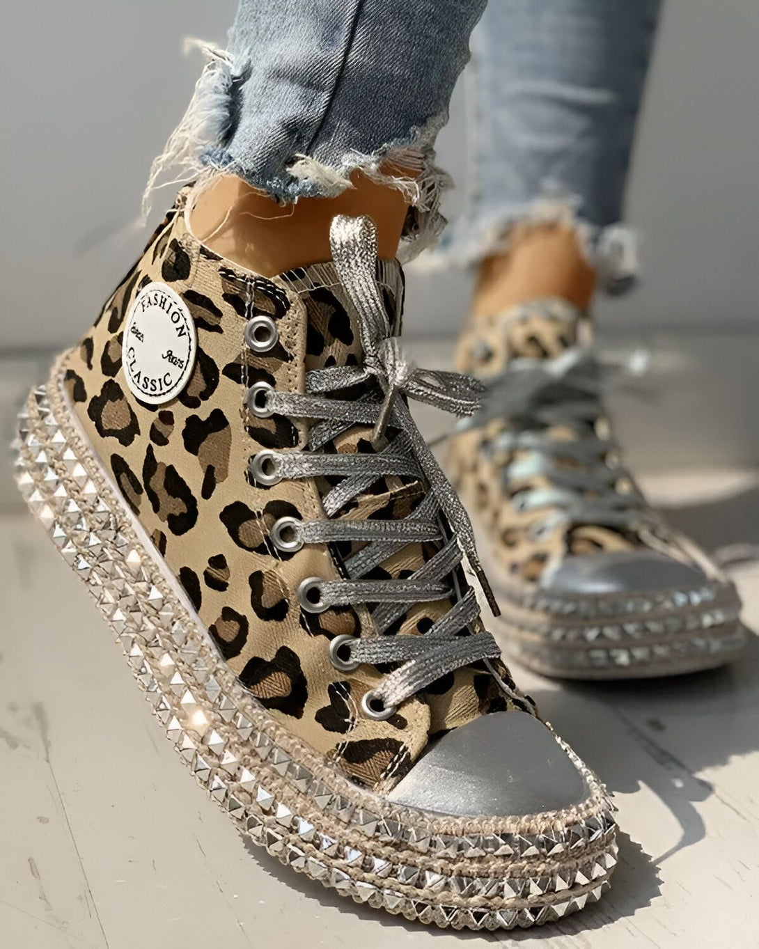 Une image d'une paire de chaussures montantes à lacets avec un motif léopard et des clous argentés sur la semelle.