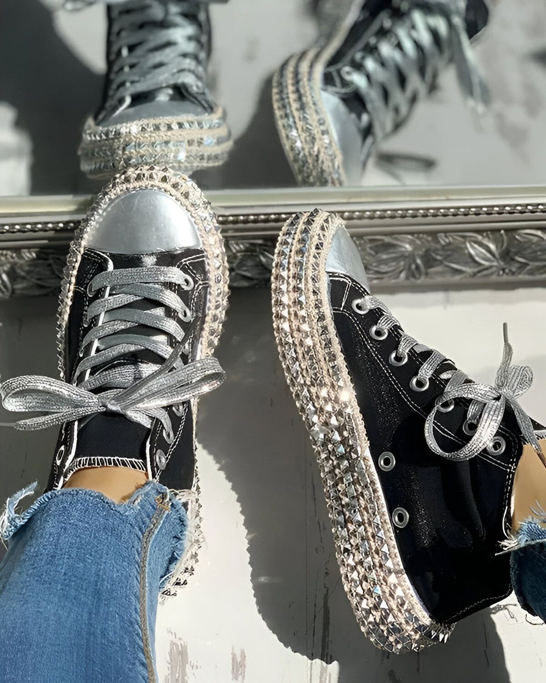 Une paire de sneakers noires et argentées avec des lacets argentés et des strass sur la semelle.