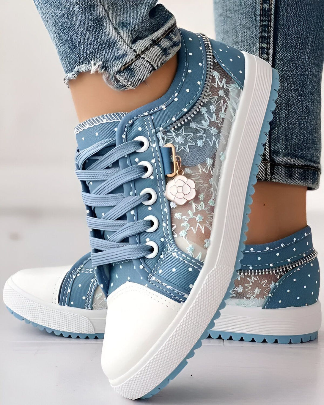 Une paire de chaussures bleues avec des lacets blancs et une semelle blanche. Les chaussures sont en toile et ont un motif floral.
