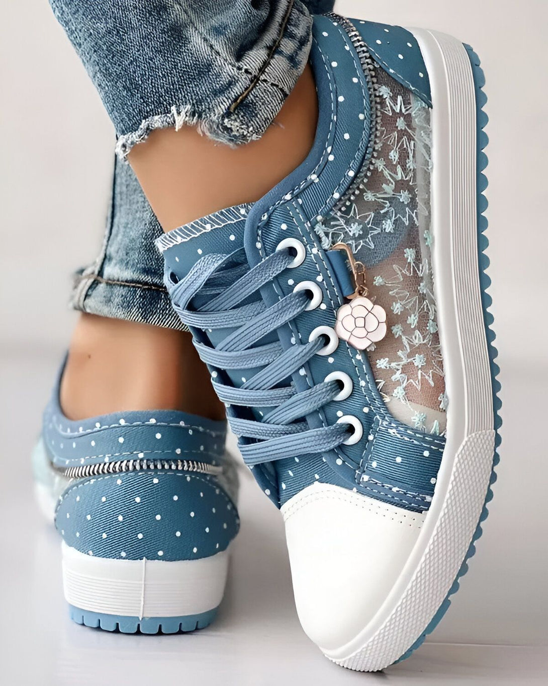 Une image de chaussures bleues avec des lacets blancs et une semelle blanche. Les chaussures sont portées par une femme qui porte des jeans bleus.