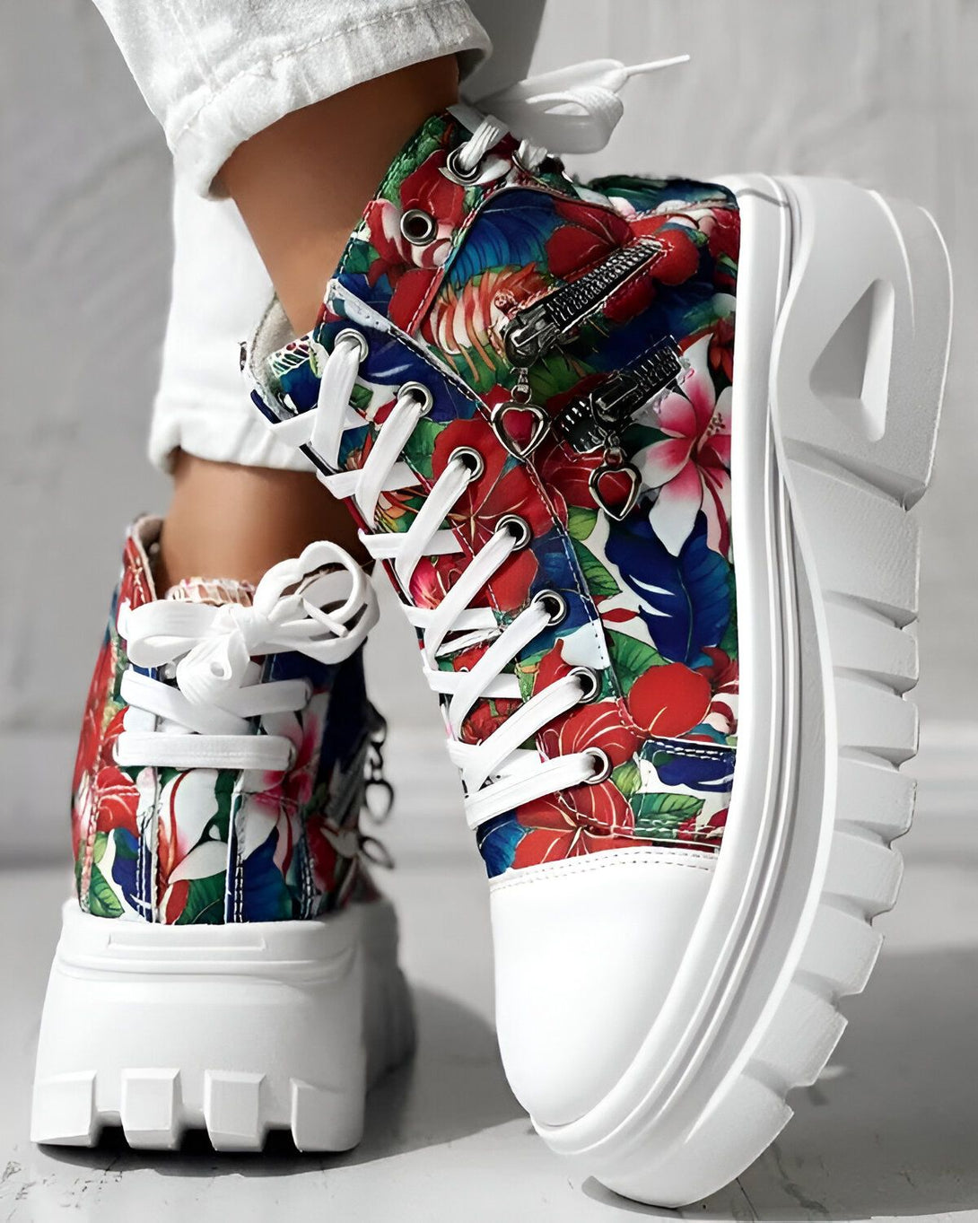 Une paire de bottes à fleurs blanches à semelles compensées avec des lacets et une fermeture éclair sur le côté.
