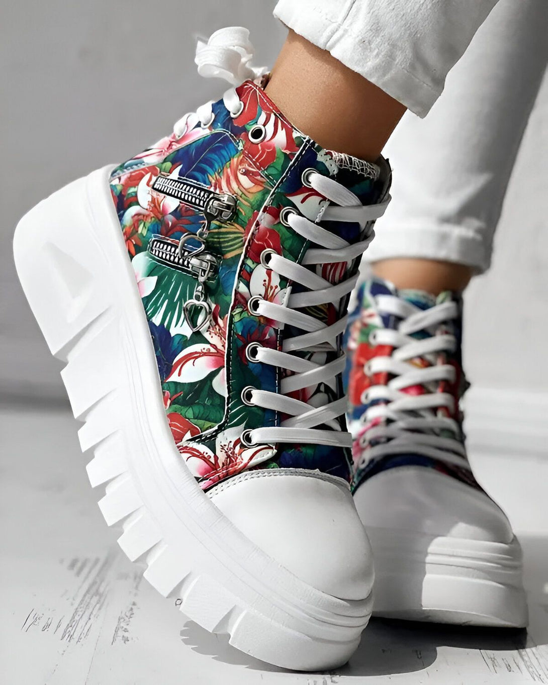 Une paire de bottes à lacets montantes à plateforme blanche à motifs floraux multicolores avec une fermeture éclair sur le côté.