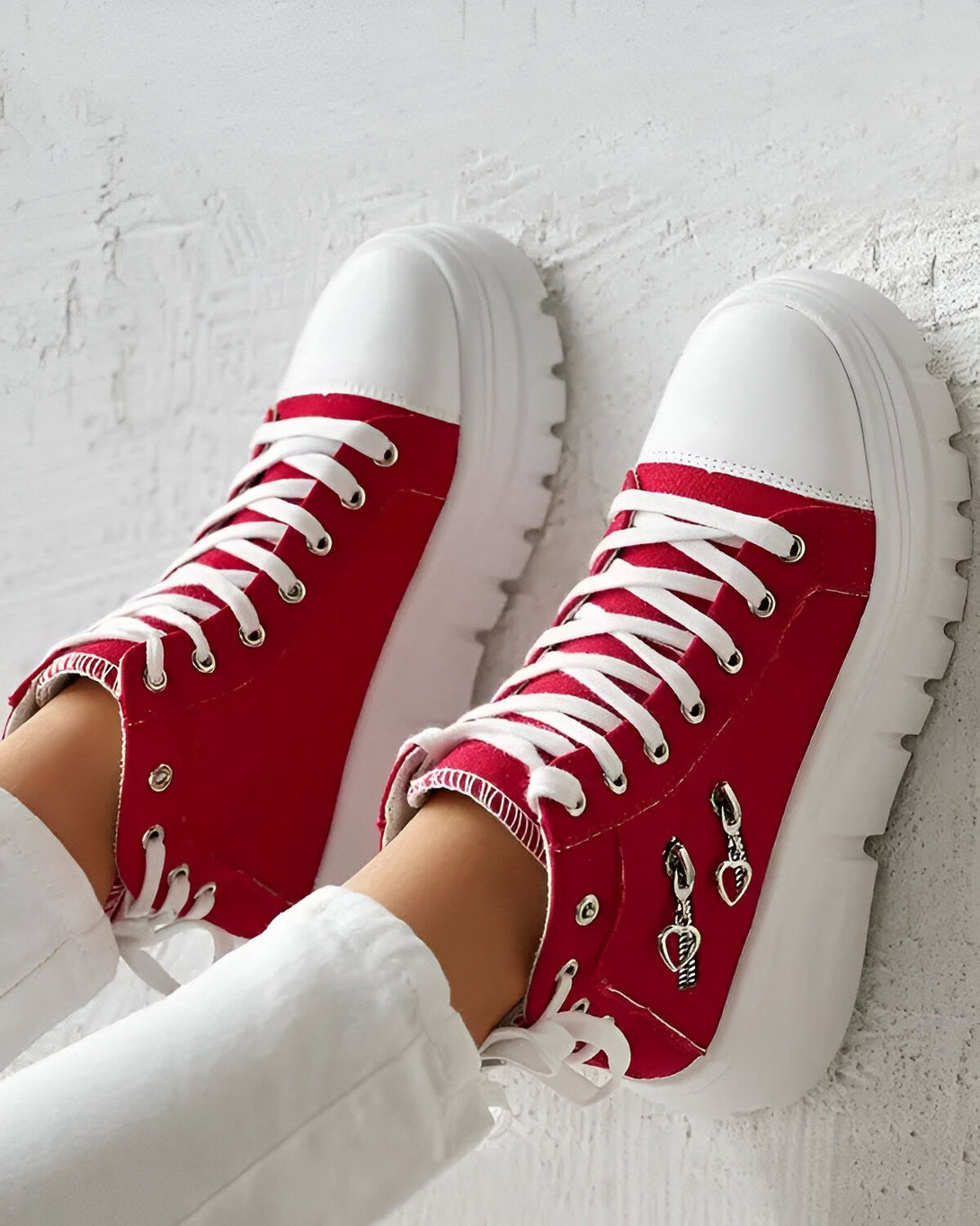 Une paire de chaussures montantes rouges et blanches avec des lacets blancs et une fermeture éclair sur le côté.