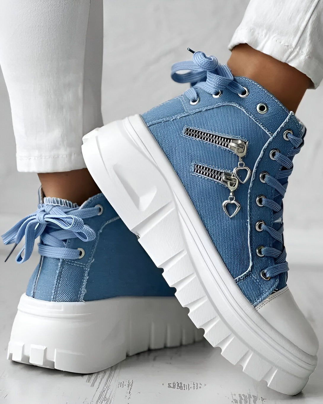 Une paire de bottes bleues à lacets avec une fermeture éclair sur le côté. Les bottes ont une semelle épaisse blanche et des lacets bleus.