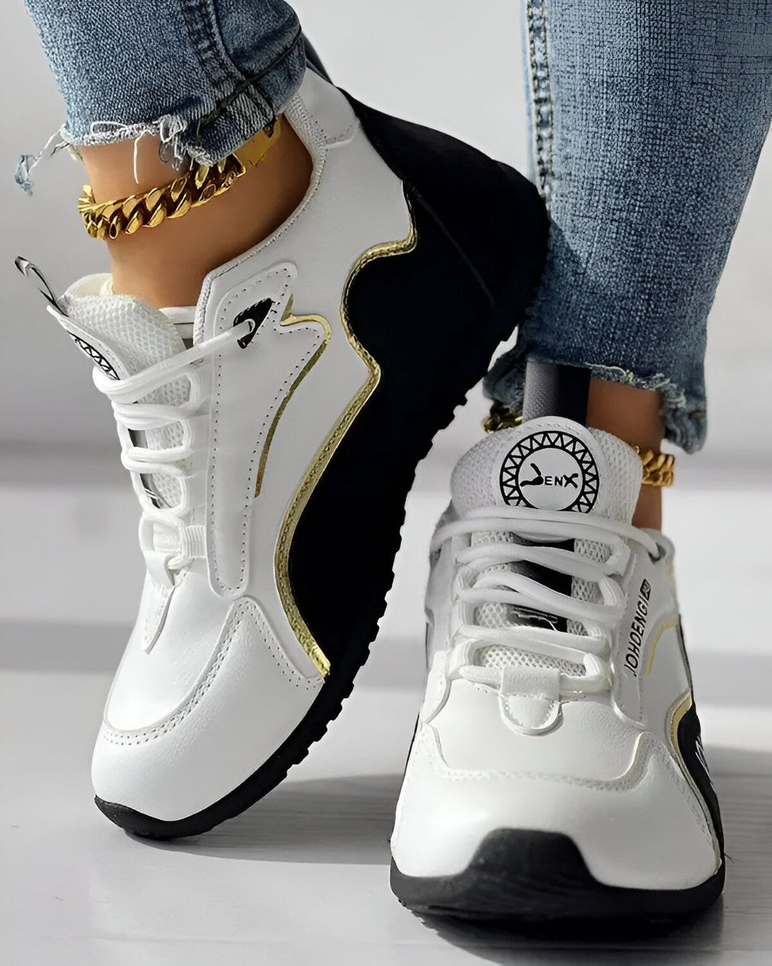Une paire de baskets blanches et noires avec des lacets blancs et une semelle noire. Le logo "J.DENG" est écrit en doré sur le côté de la basket.