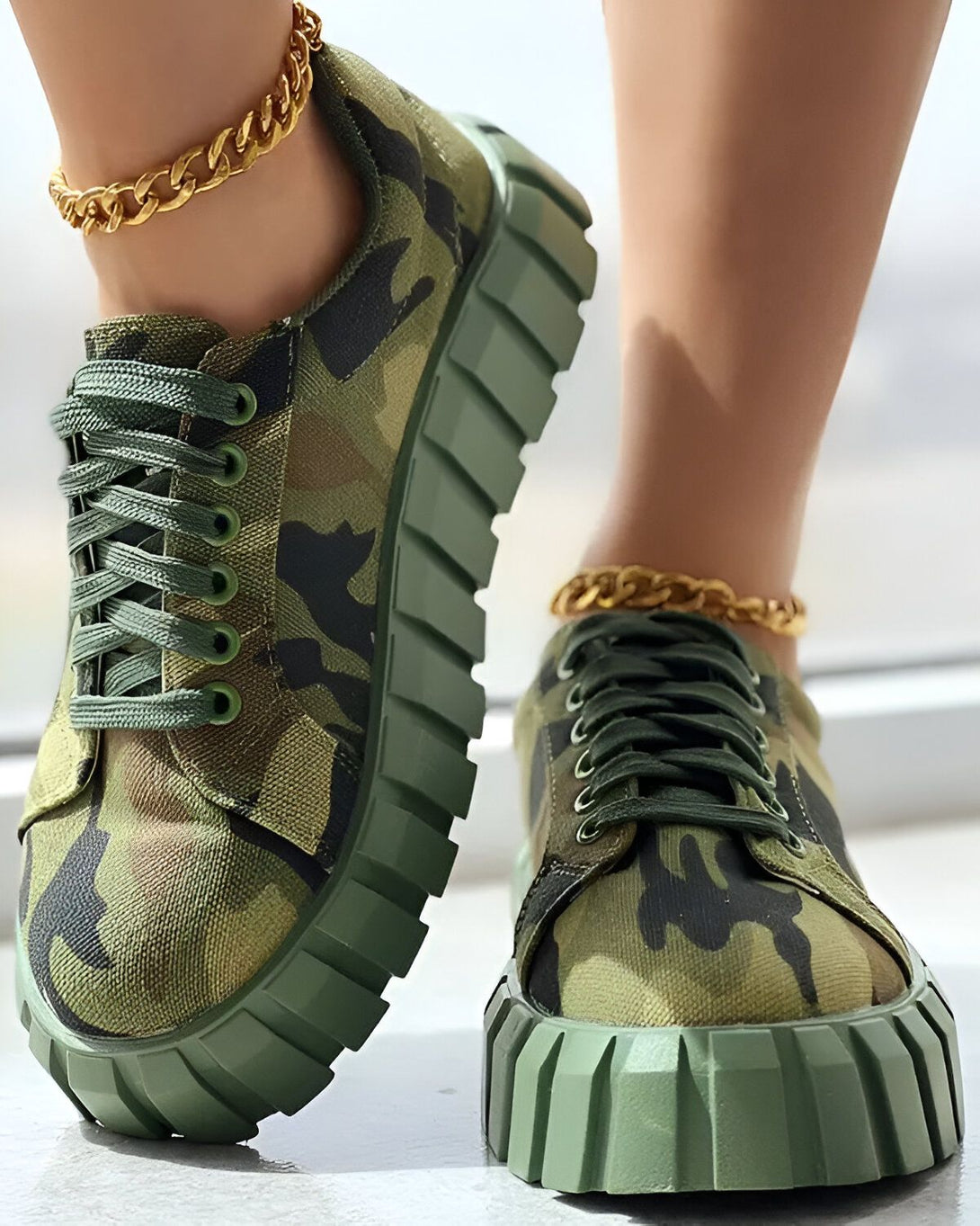 Une femme porte des baskets vertes et blanches avec un motif camouflage. Les baskets sont lacées avec des lacets verts. La femme porte également des chaussettes blanches et un pantalon cargo vert.