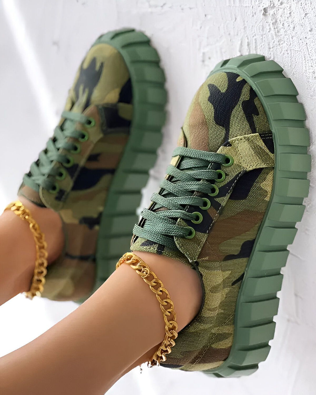 Une paire de baskets vert kaki à lacets avec un motif camouflage.
