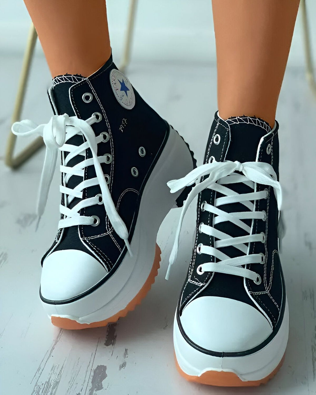 Une paire de chaussures montantes noires à lacets avec une semelle compensée blanche et marron.