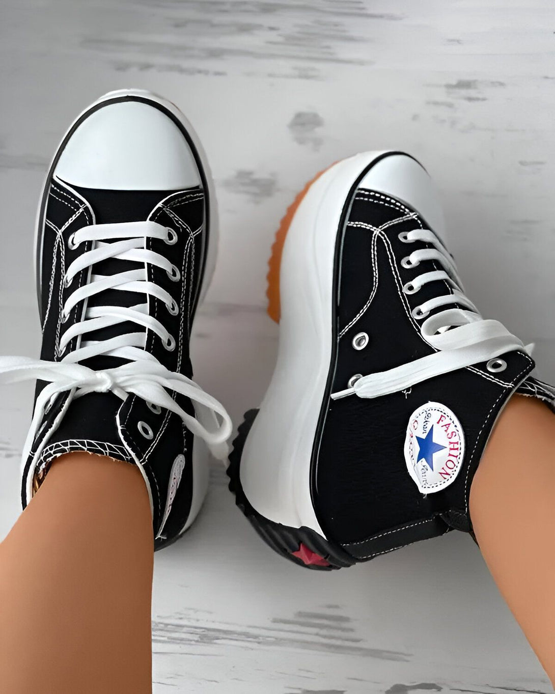 Une paire de chaussures montantes noires et blanches avec des lacets blancs. Les chaussures ont une semelle épaisse et crantée.