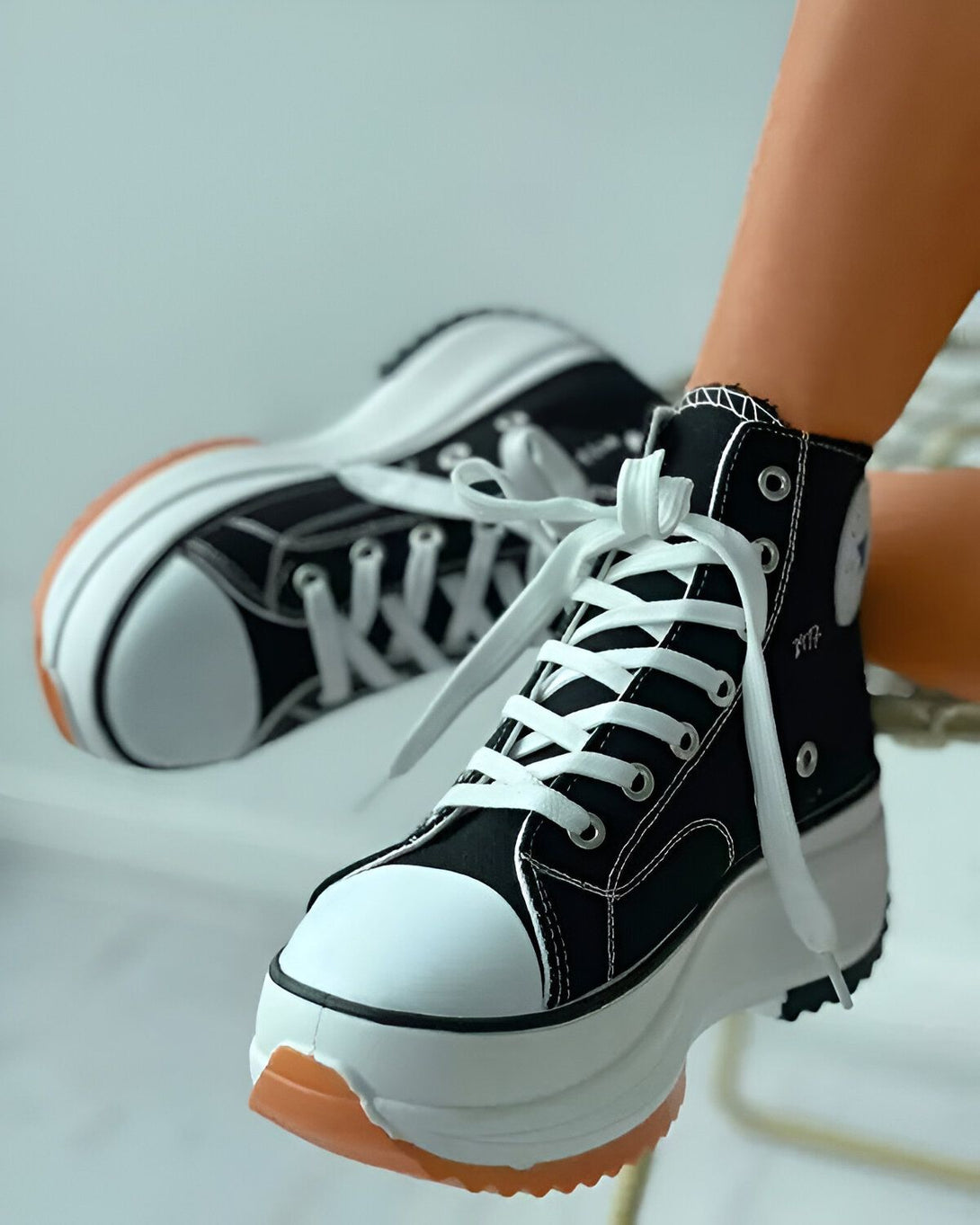 Une image d'une paire de chaussures montantes noires et blanches avec des lacets blancs. Les chaussures sont portées par un mannequin et sont vues de côté.