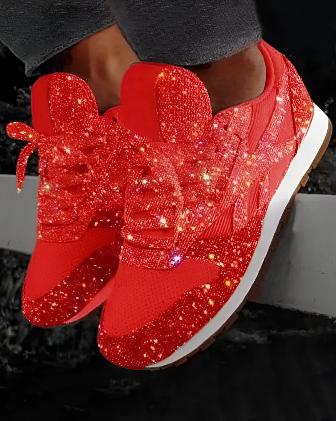 Une paire de sneakers rouge pailletée est posée sur un muret.