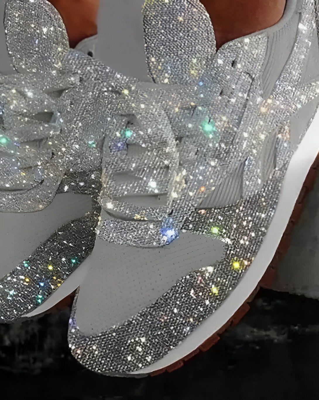 Une paire de baskets grises avec des lacets et des détails scintillants argentés.