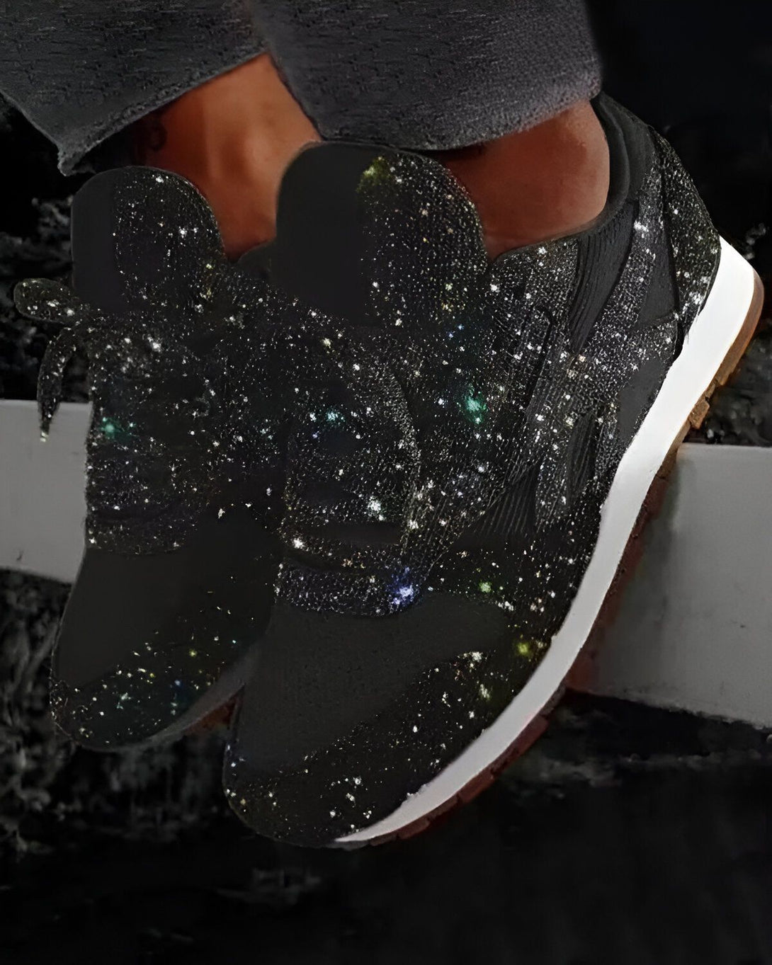 Une paire de sneakers noires avec des étoiles multicolores qui brillent.