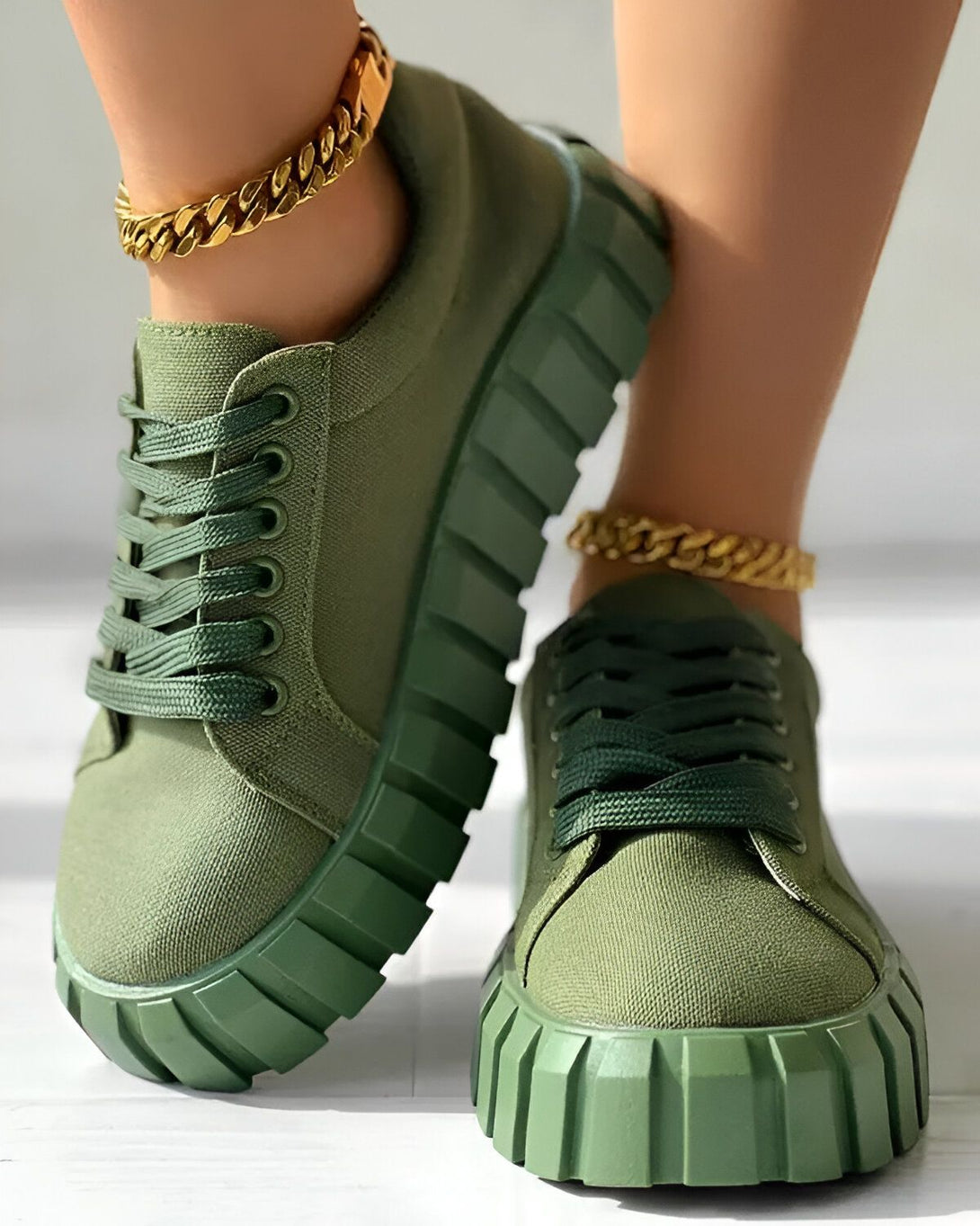 Une paire de baskets vertes avec des lacets verts sur un sol en béton.