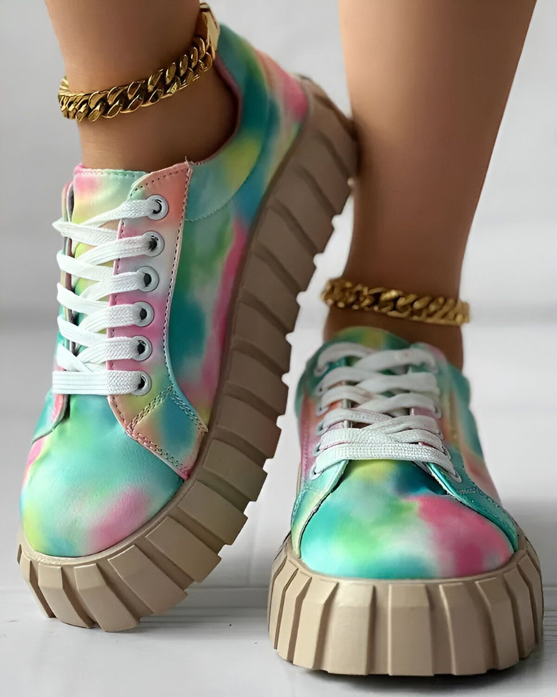 Une paire de baskets tie-dye colorées avec des lacets blancs et une semelle épaisse.