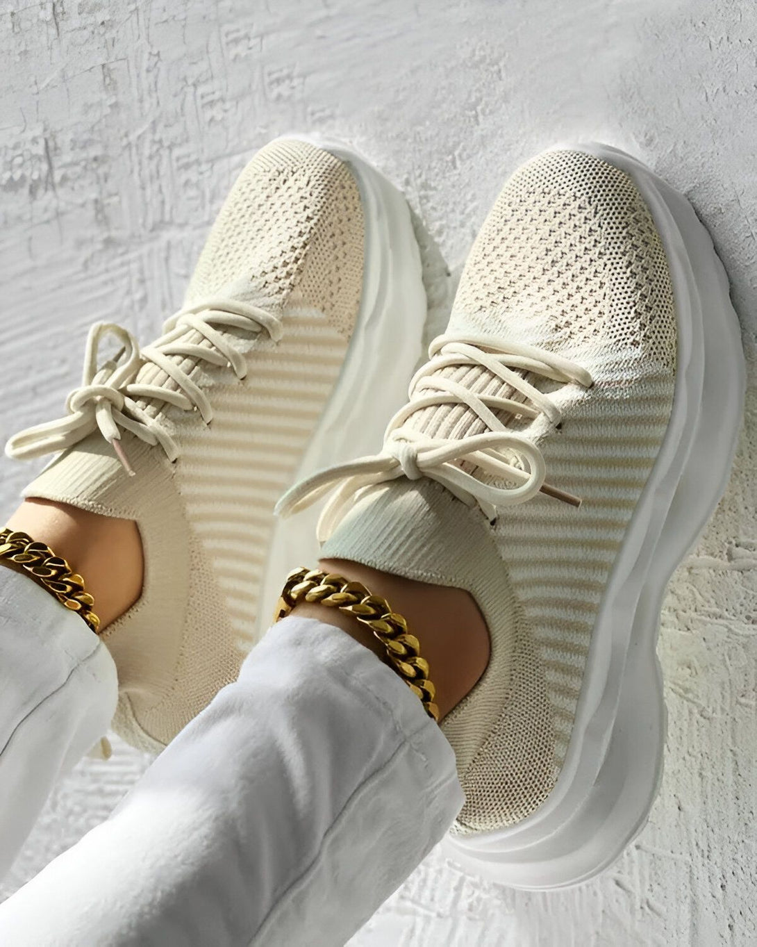 Une paire de baskets beiges avec des lacets beiges sur un fond blanc.