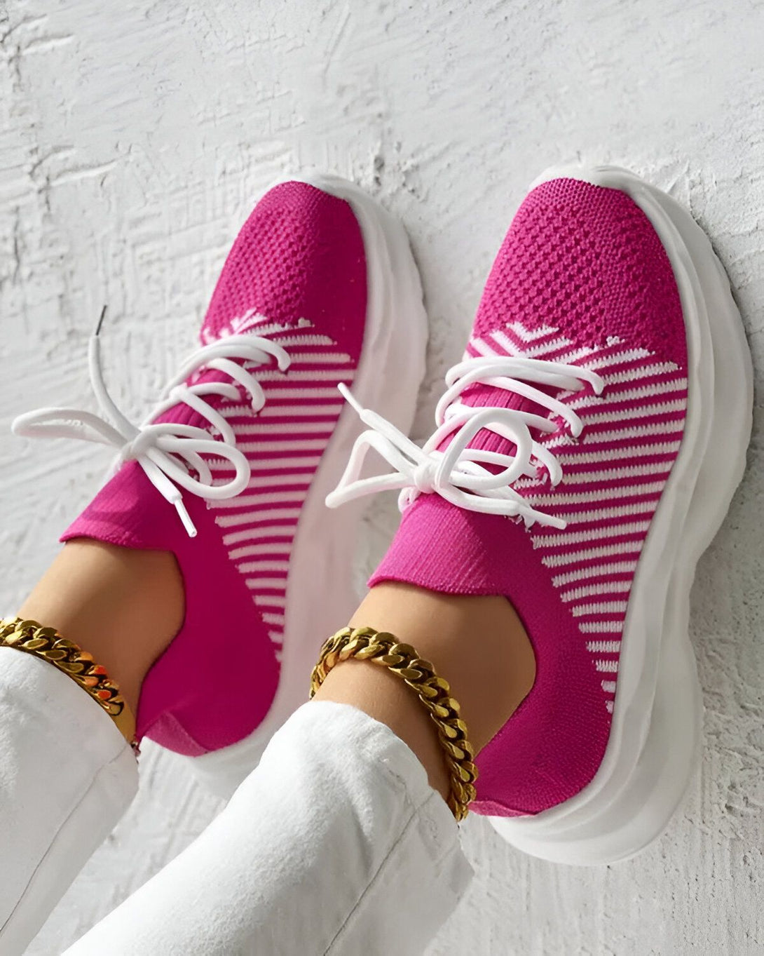 Une paire de baskets roses et blanches à lacets avec une semelle épaisse.