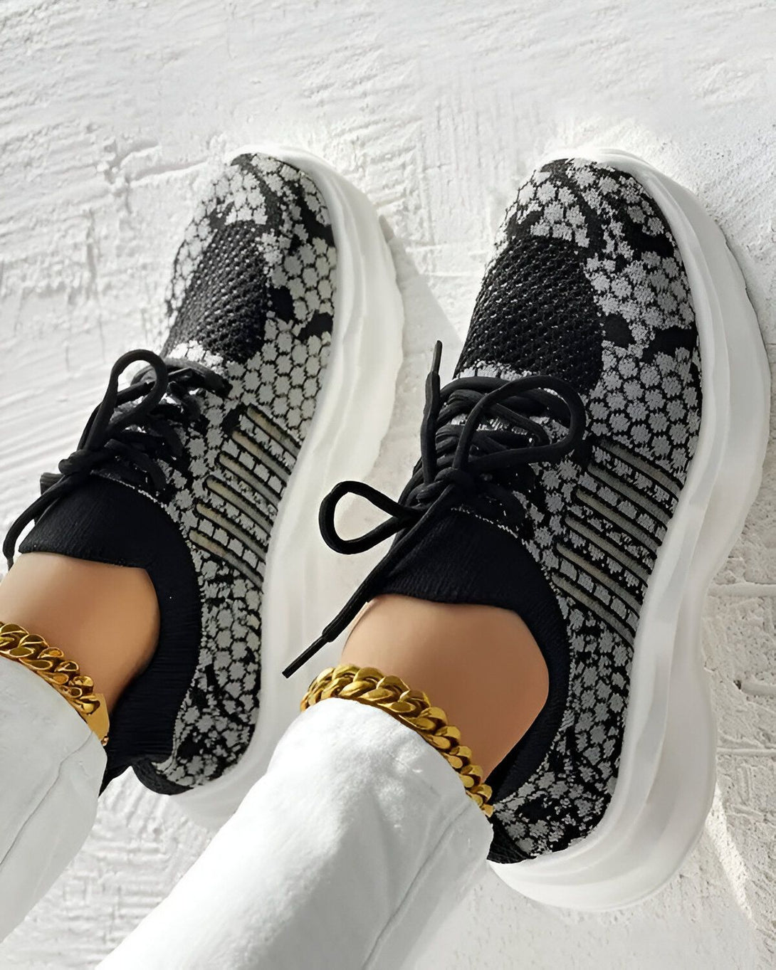Une paire de baskets noires et grises avec des lacets noirs sur un fond blanc.