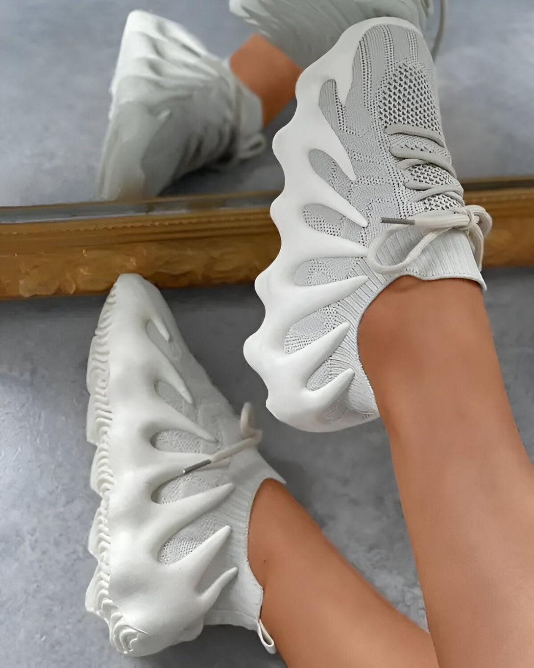 Une paire de chaussures de sport grises à lacets avec une semelle épaisse et crantée.