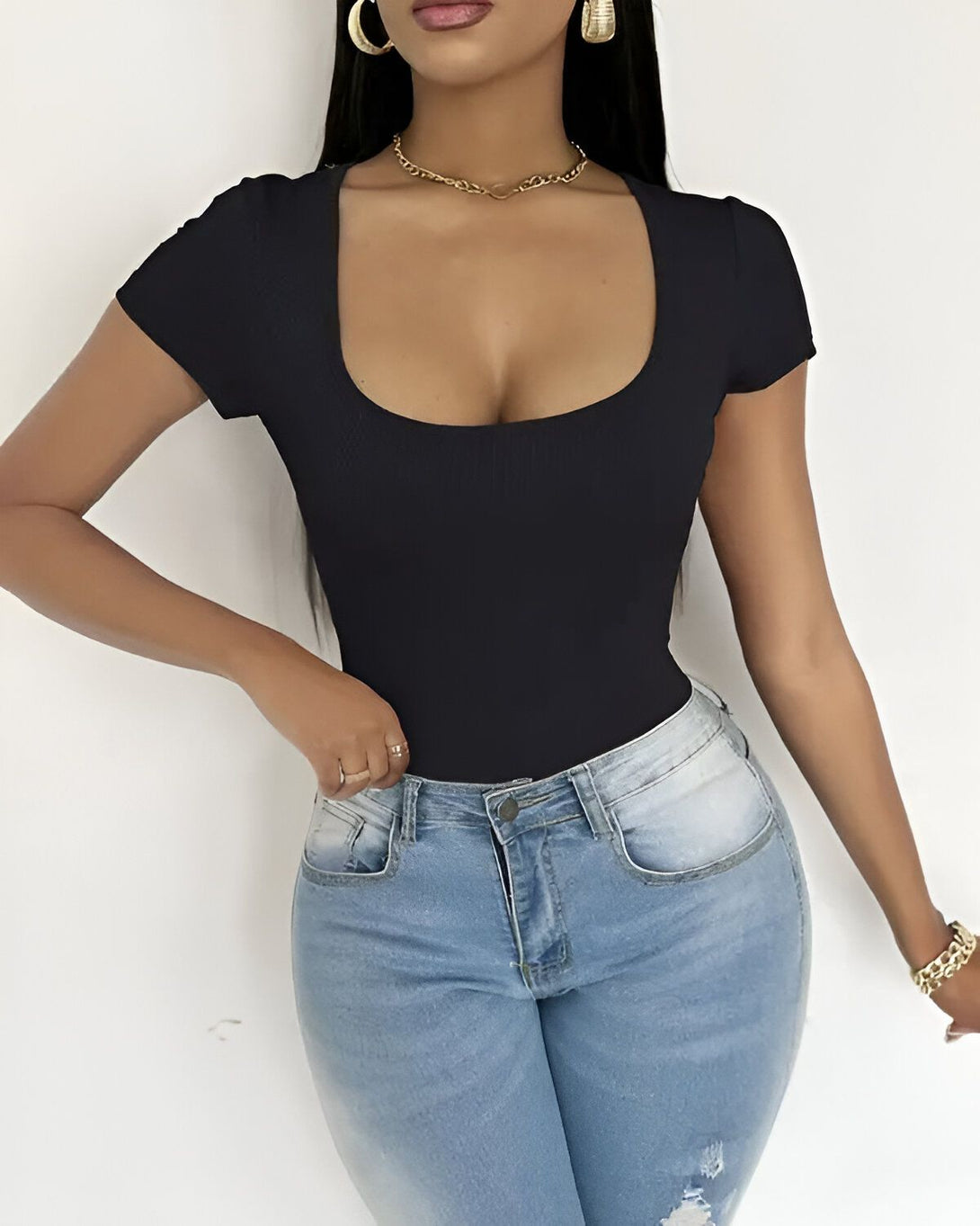 Une jeune femme porte un body noir moulant à manches courtes et un jean bleu taille haute.