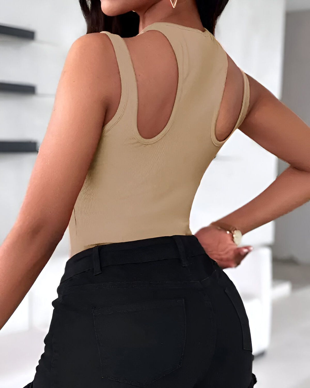 Une femme porte un body beige dos nu et un jean noir.