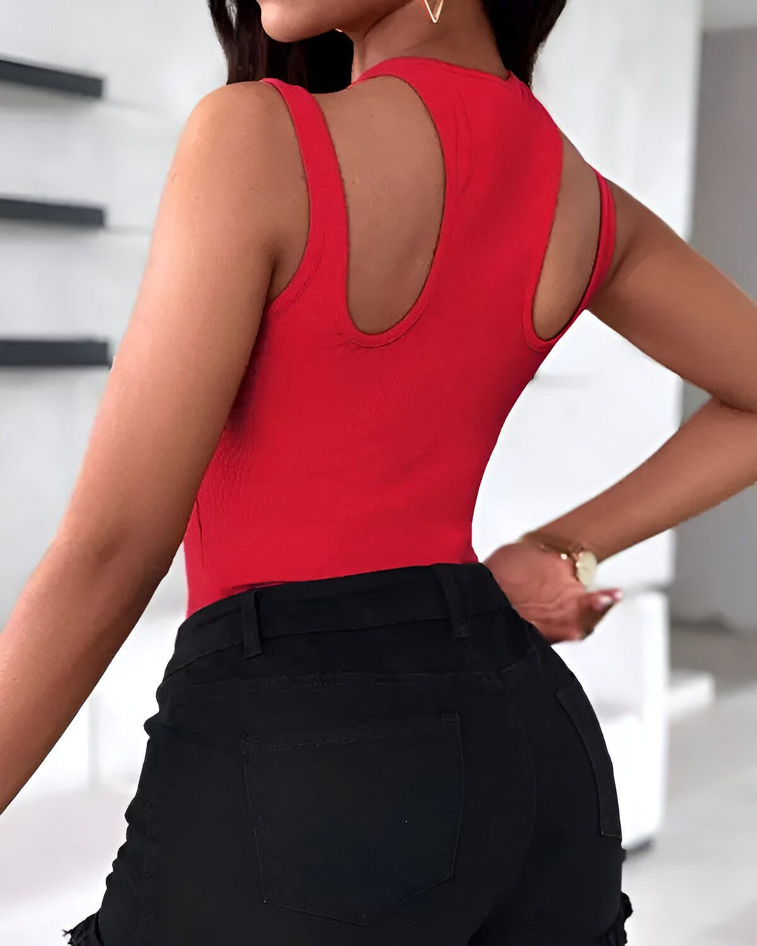 Une femme porte un body moulant rouge dos nu et un short en jean noir taille haute.