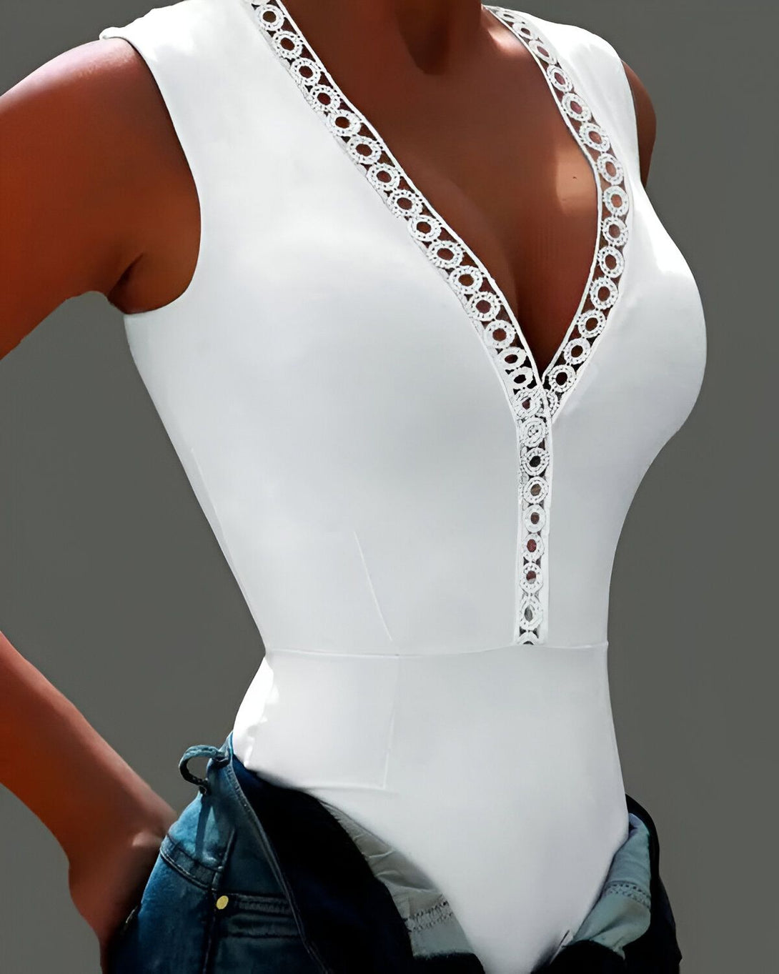 Le mannequin porte un body blanc moulant avec des détails en dentelle sur le devant. Il est associé à un jean bleu.