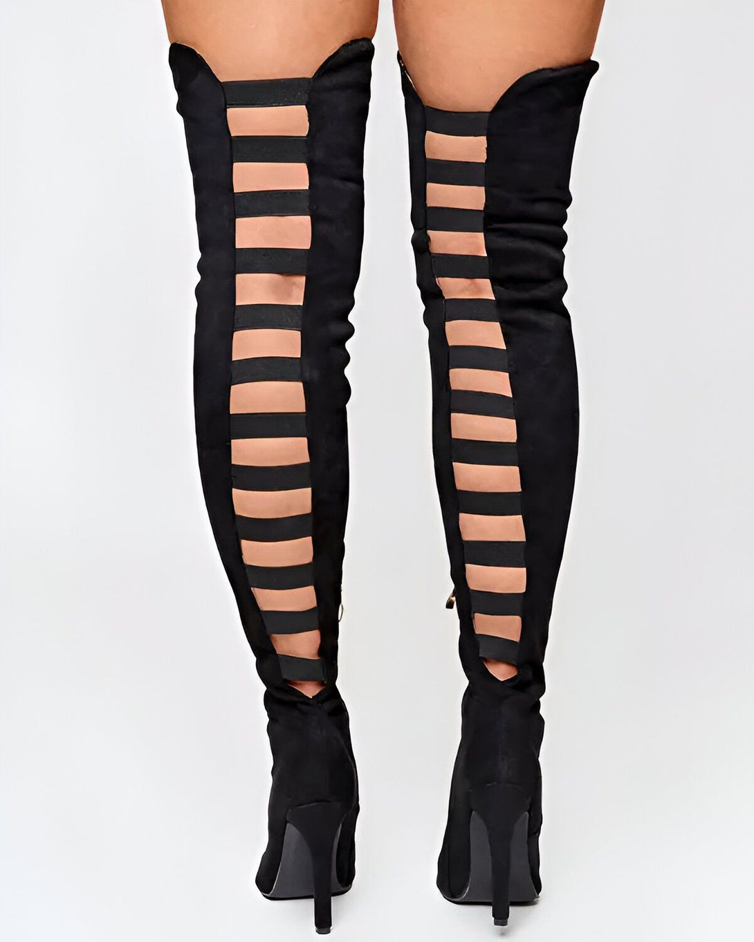 Une femme porte des bottes noires à talons hauts. Les bottes sont ouvertes à l'arrière et ont des lanières qui montent jusqu'en haut de la cuisse.