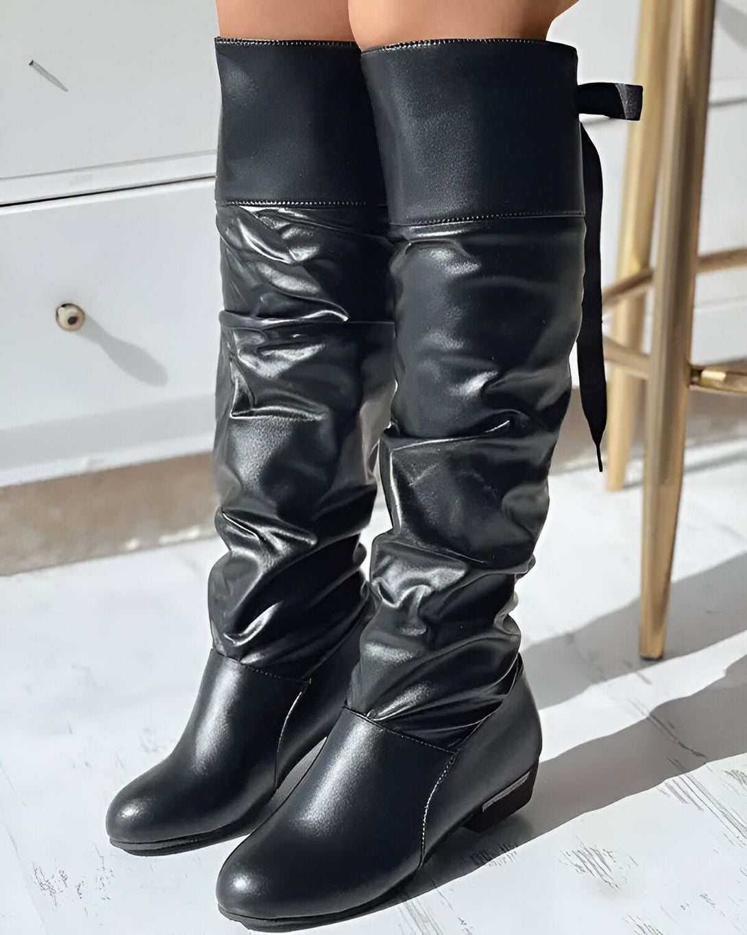Une paire de bottes noires en cuir véritable, avec un talon de 5 cm. Les bottes sont munies d'un laçage sur le côté.