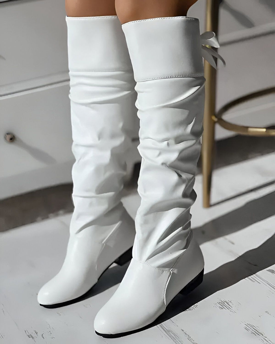 Une paire de bottes blanches à talons, avec un nœud sur le côté.