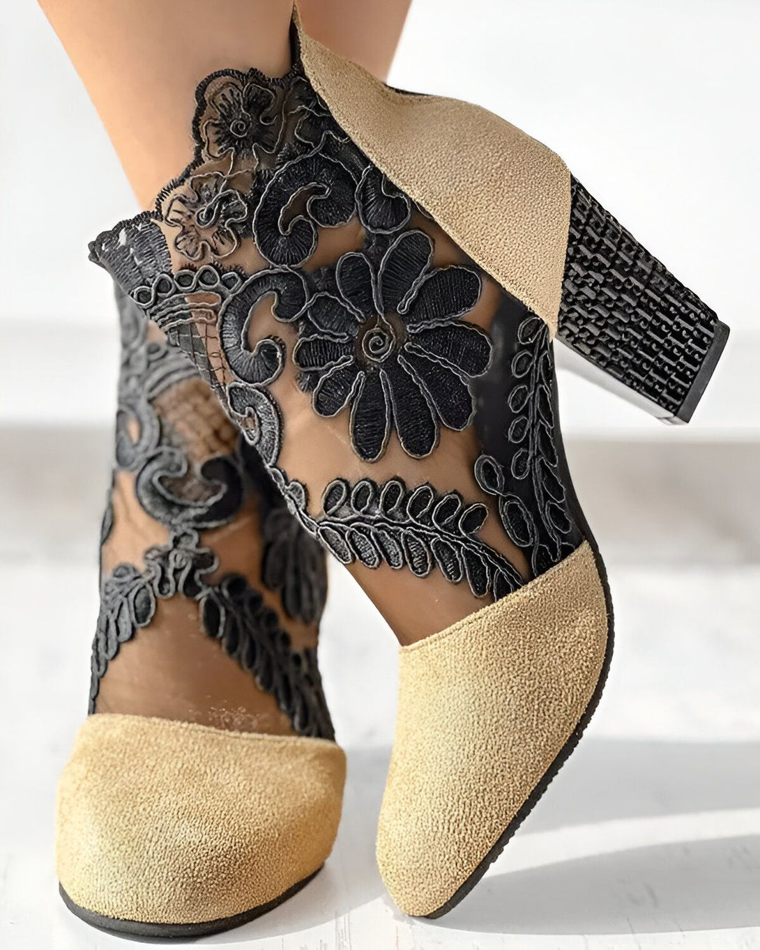 Une image de chaussures à talons hauts beiges et noirs. Les chaussures sont en daim beige avec un empiècement en dentelle noire sur le dessus. Le talon est noir et mesure environ 10 cm.