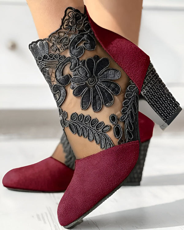 Une paire de bottines rouges à talons hauts avec un empiècement en dentelle noire sur le côté.