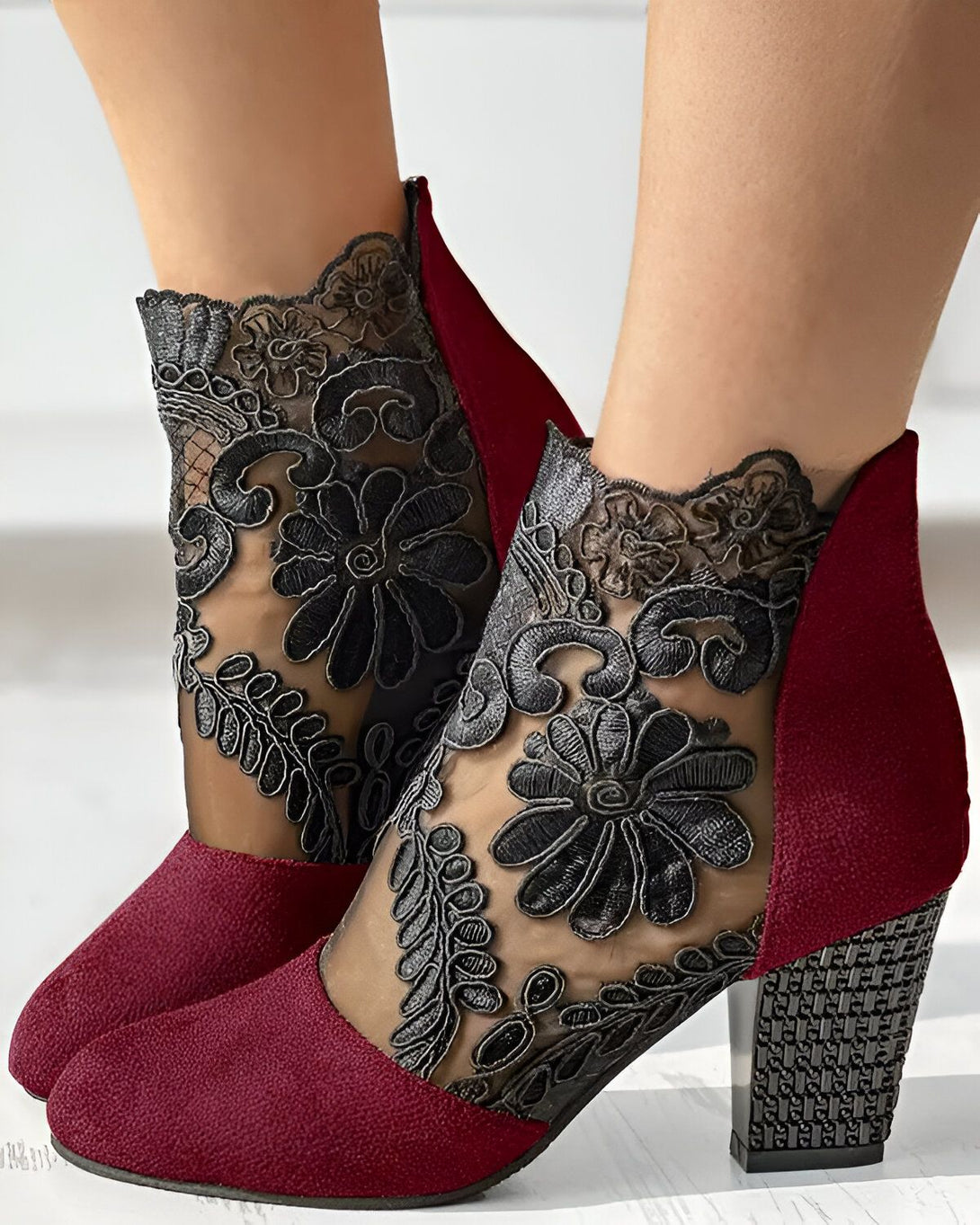Une paire de bottines rouges à talons hauts avec un bout pointu et une tige en dentelle noire.