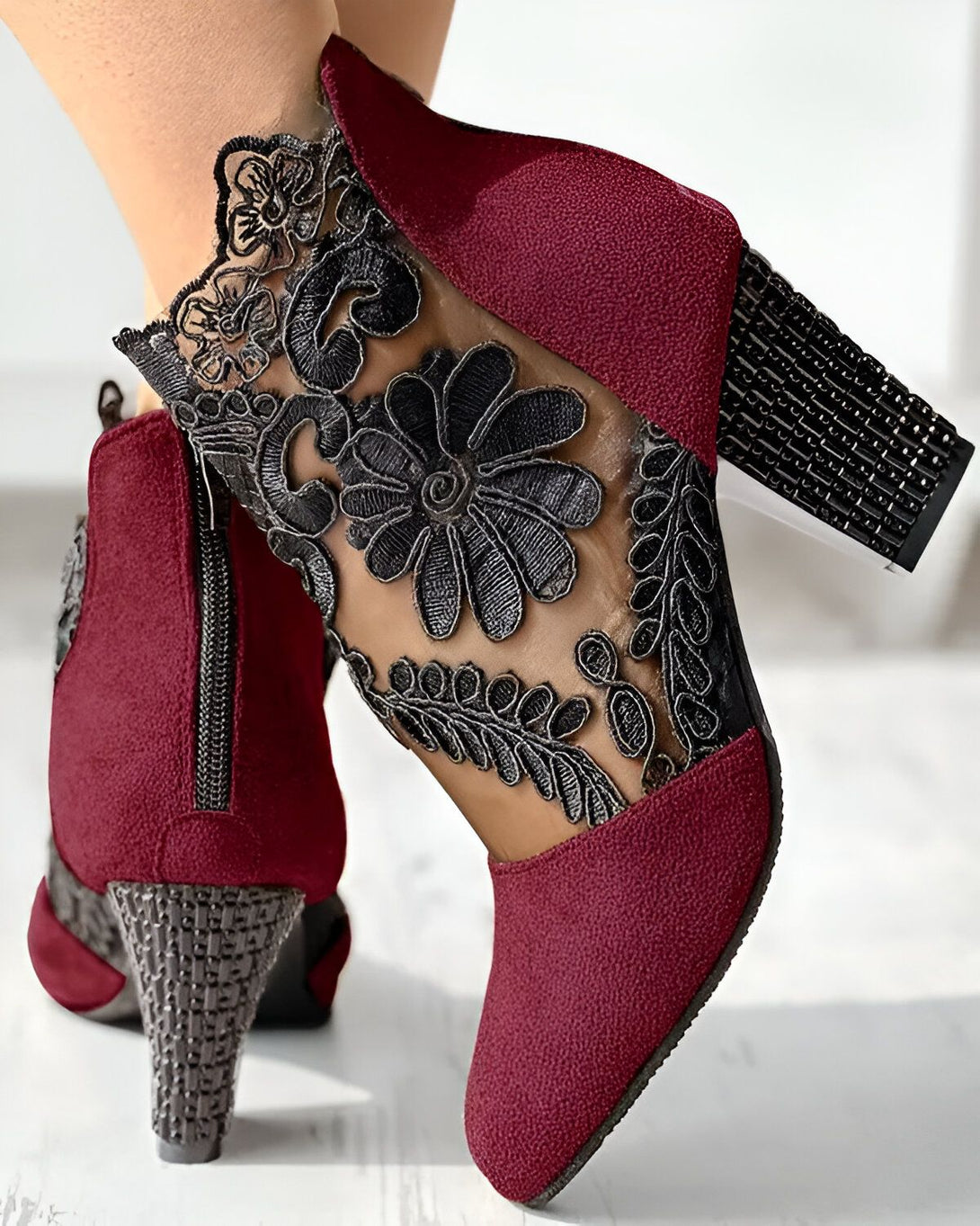 Une paire de bottines rouges à talons hauts avec un empiècement en dentelle noire sur le côté.