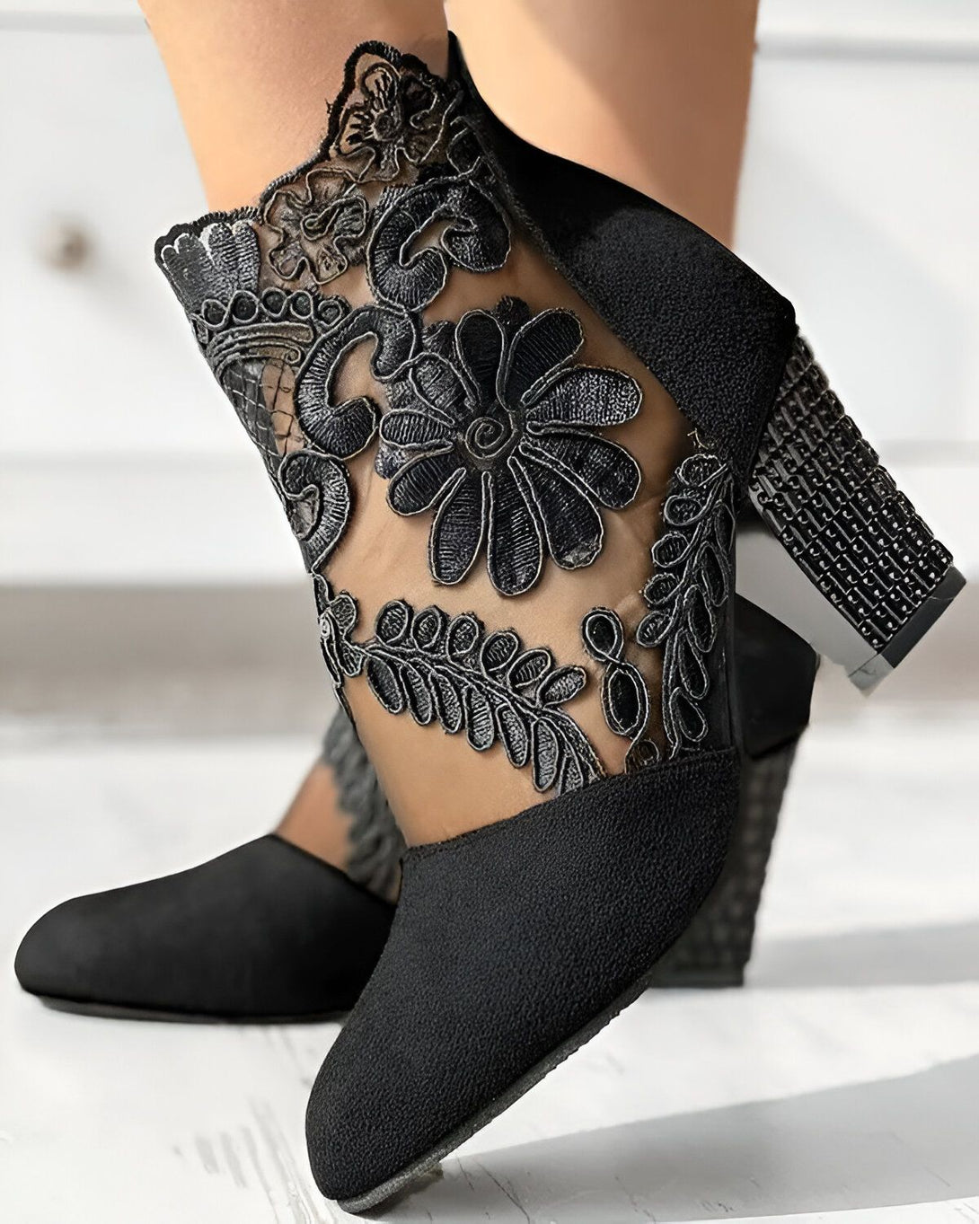 Une image de chaussures à talons noirs avec des fleurs en dentelle.