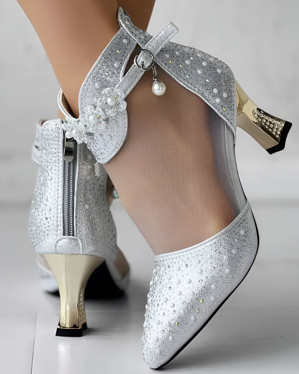 Une paire d'escarpins argentés à talons hauts avec des fleurs en perles sur le côté.