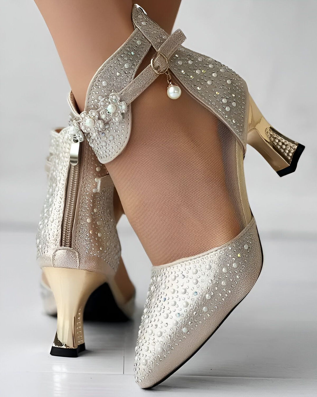 Une image de chaussures à talons hauts dorées avec des perles et des strass. Les chaussures sont portées par une femme.