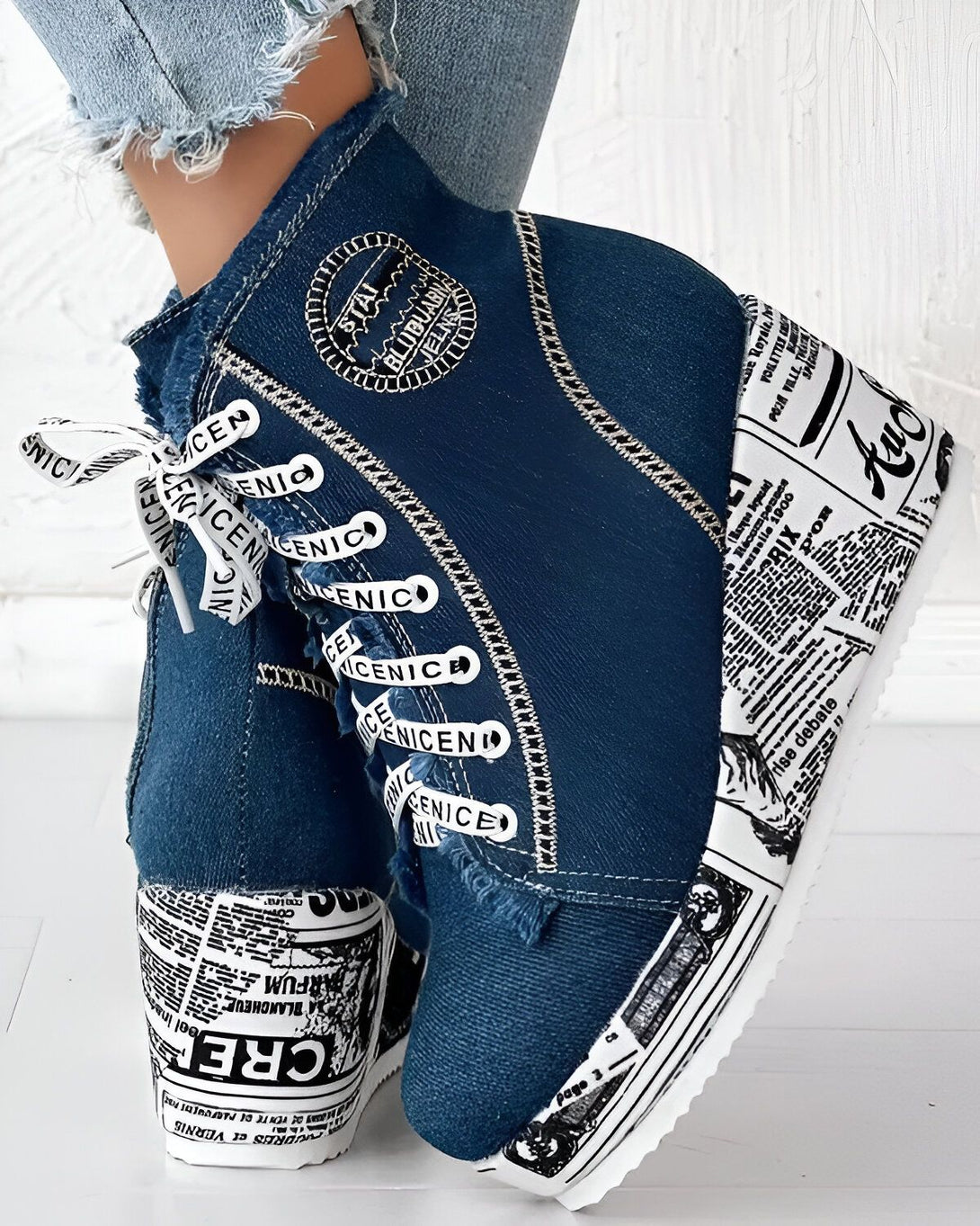 Une image d'une paire de chaussures compensées en jean bleu avec des lacets blancs et des semelles à motifs de journaux.