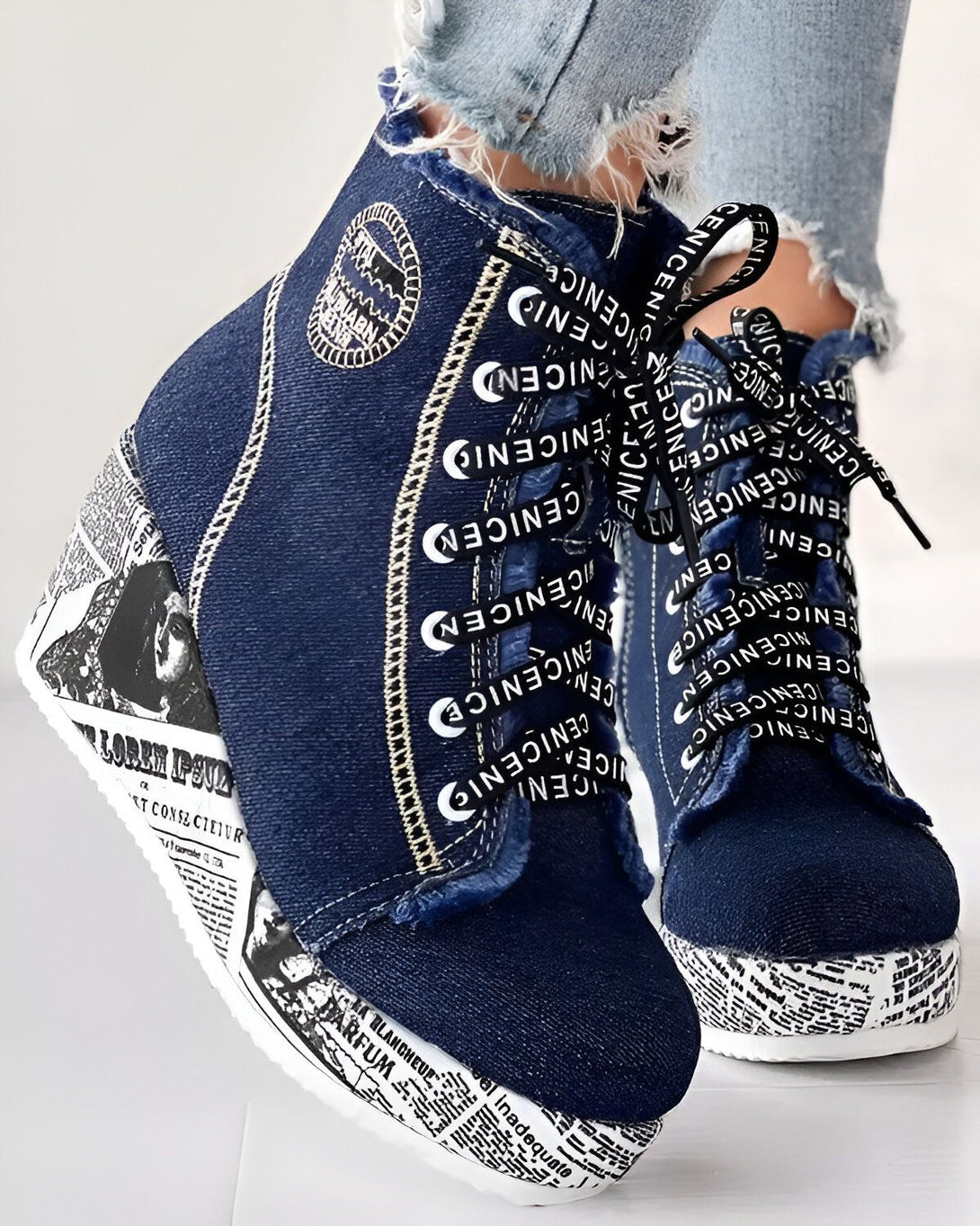Une paire de chaussures compensées en jean bleu avec des lacets blancs et une semelle noire.