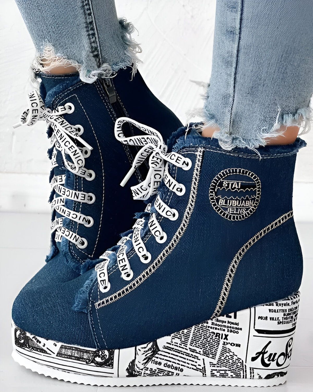 Une paire de bottines compensées en jean bleu avec des lacets blancs et une fermeture éclair sur le côté.