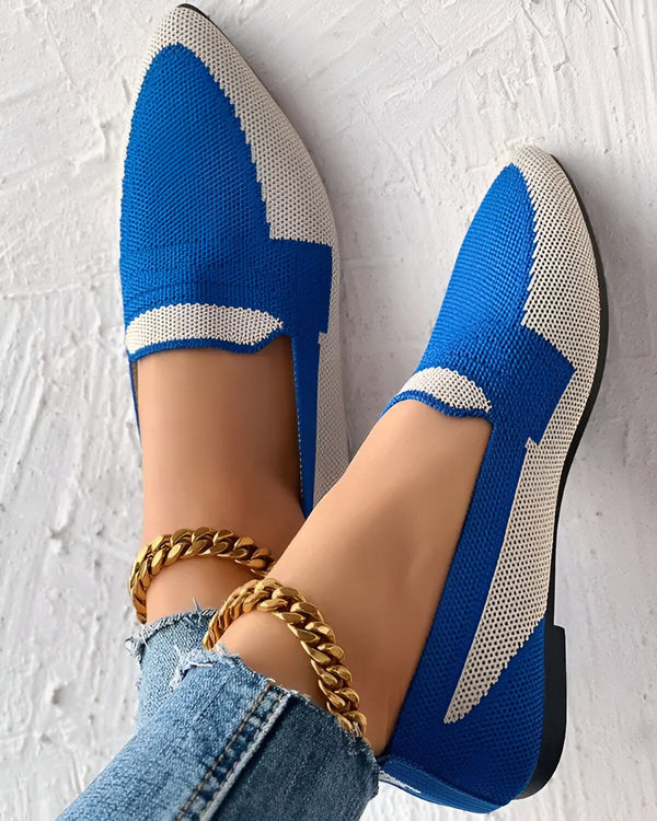 Une paire de chaussures bleues et blanches avec un motif en forme de losange. Les chaussures sont portées par une femme qui porte également un jean et une cheville dorée.