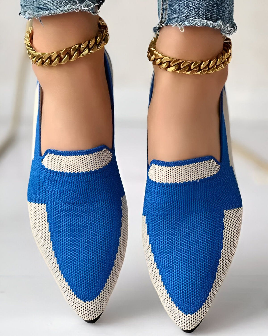 Une femme porte des chaussures bleues et blanches avec des semelles blanches. Elle porte également des bracelets de cheville en or.