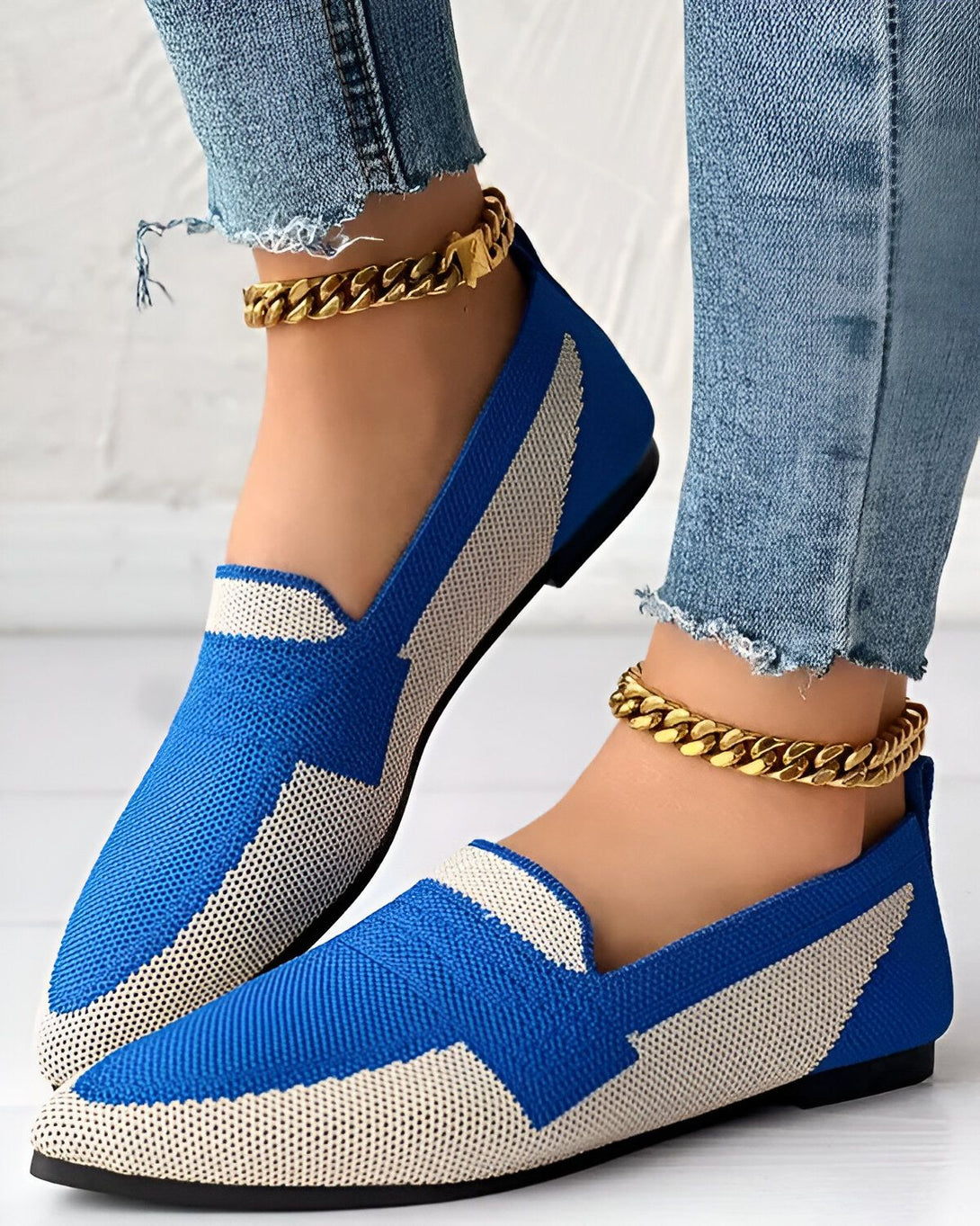 Une image de chaussures bleues et blanches avec des chaînes dorées autour des chevilles du modèle.